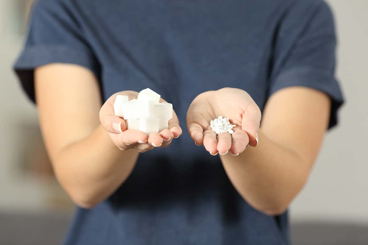 woman holding sugar cubes and saccharin pills