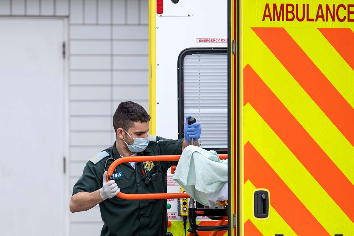 A London health care worker takes a man from an ambulance.