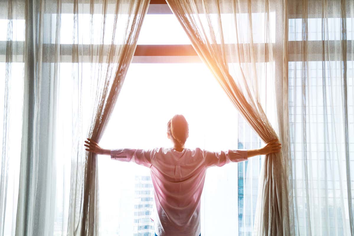Woman opening curtains
