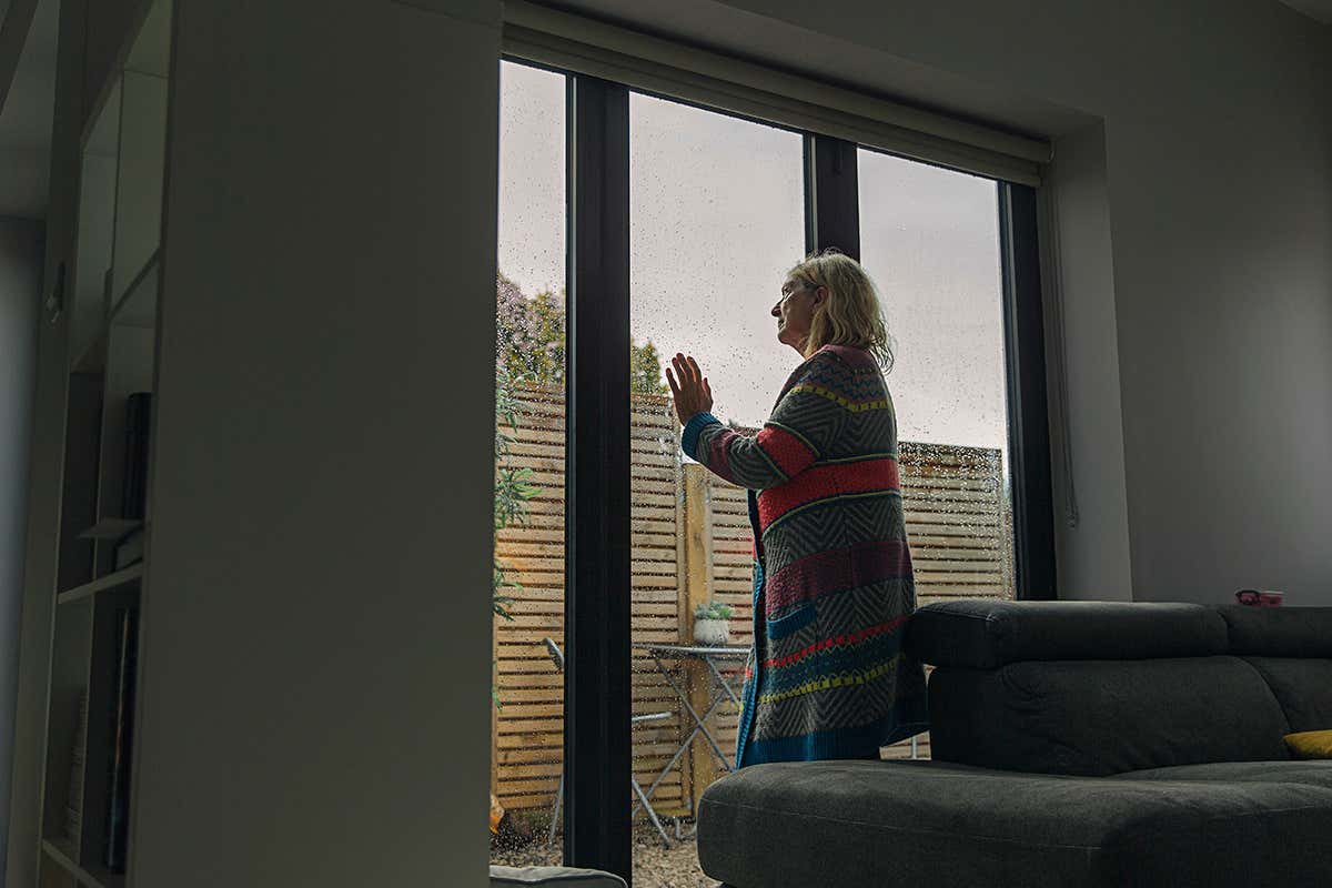 Woman looking through wet window