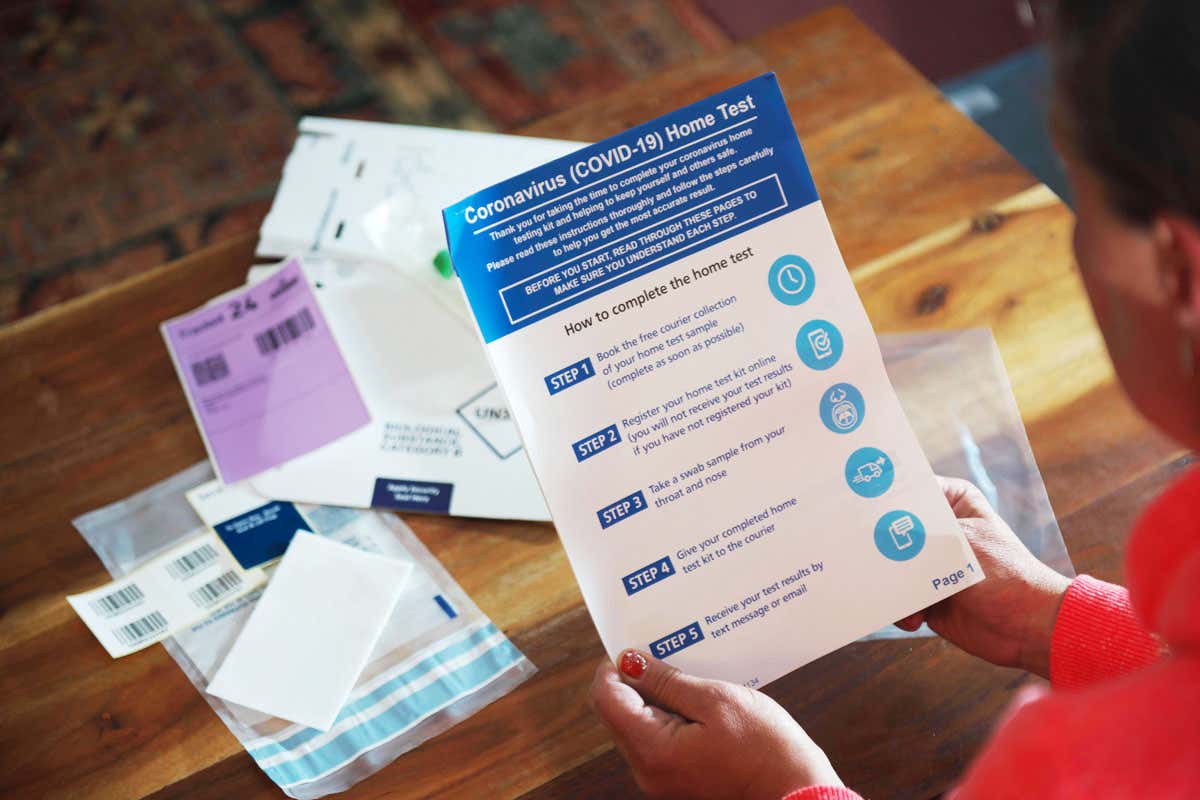 middle aged young looking white female sits at home reading through Covid19 home testing kit supplied by UK government