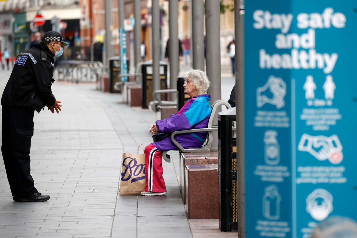 A police officer talks to a woman as he patrols along a street, following a local lockdown in Leicester