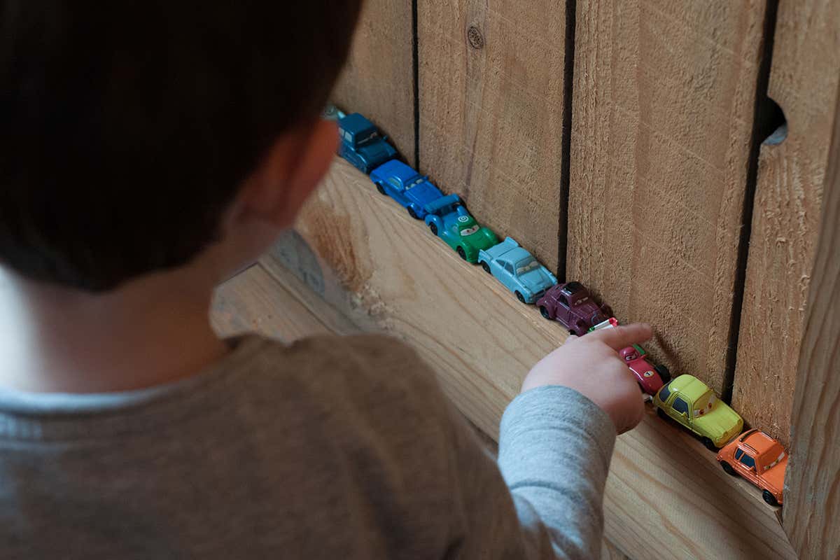 An autistic boy playing with little car toys