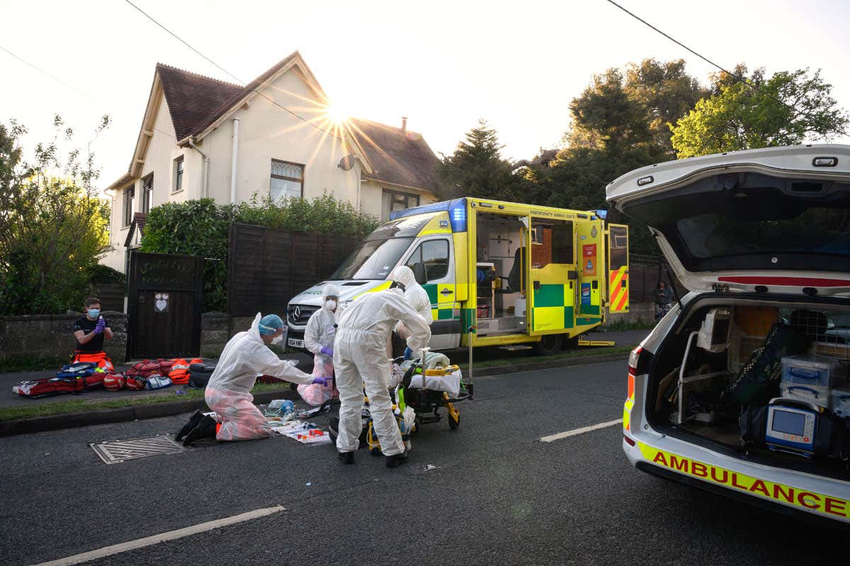 Ambulance crews treat a patient with possible COVID-19 symptoms