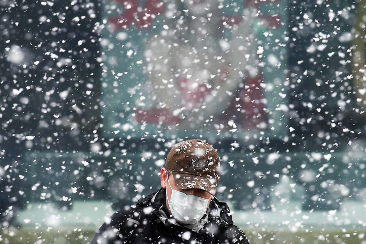 Man wearing mask and hat in snow