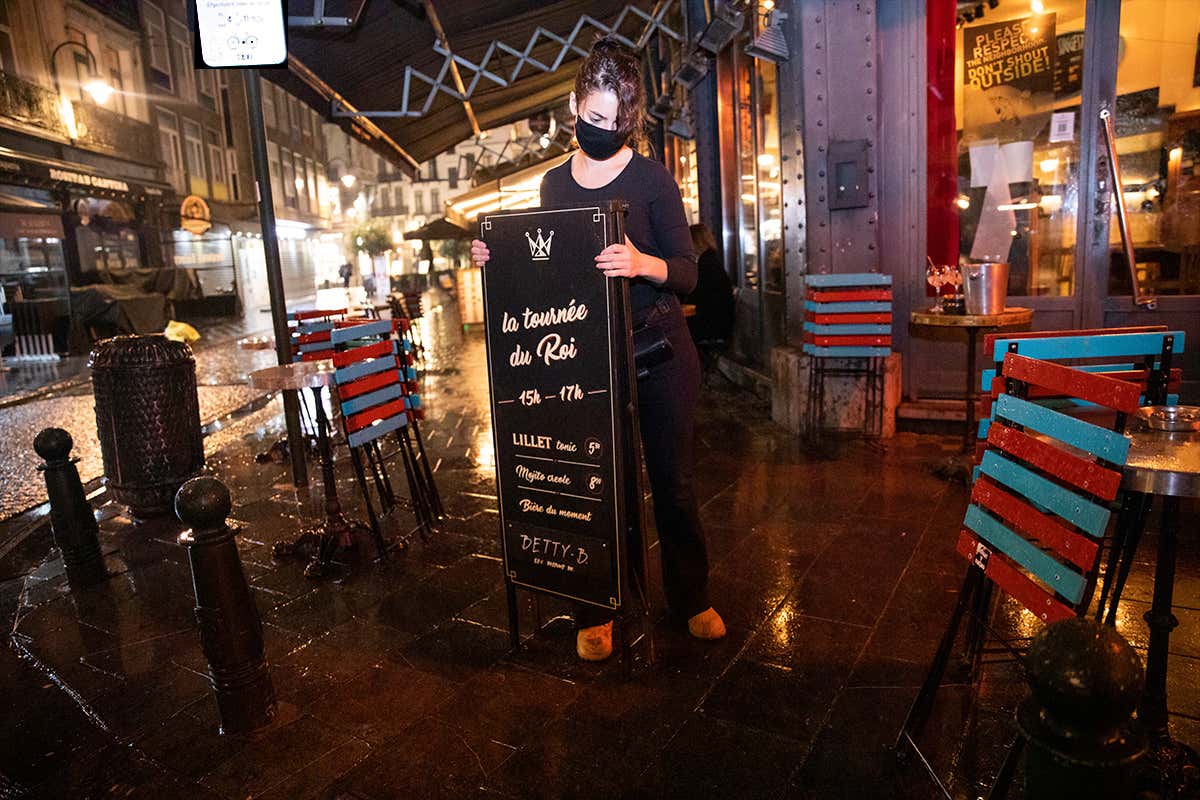 A restaurant employee removes chairs on a terrace in Brussels