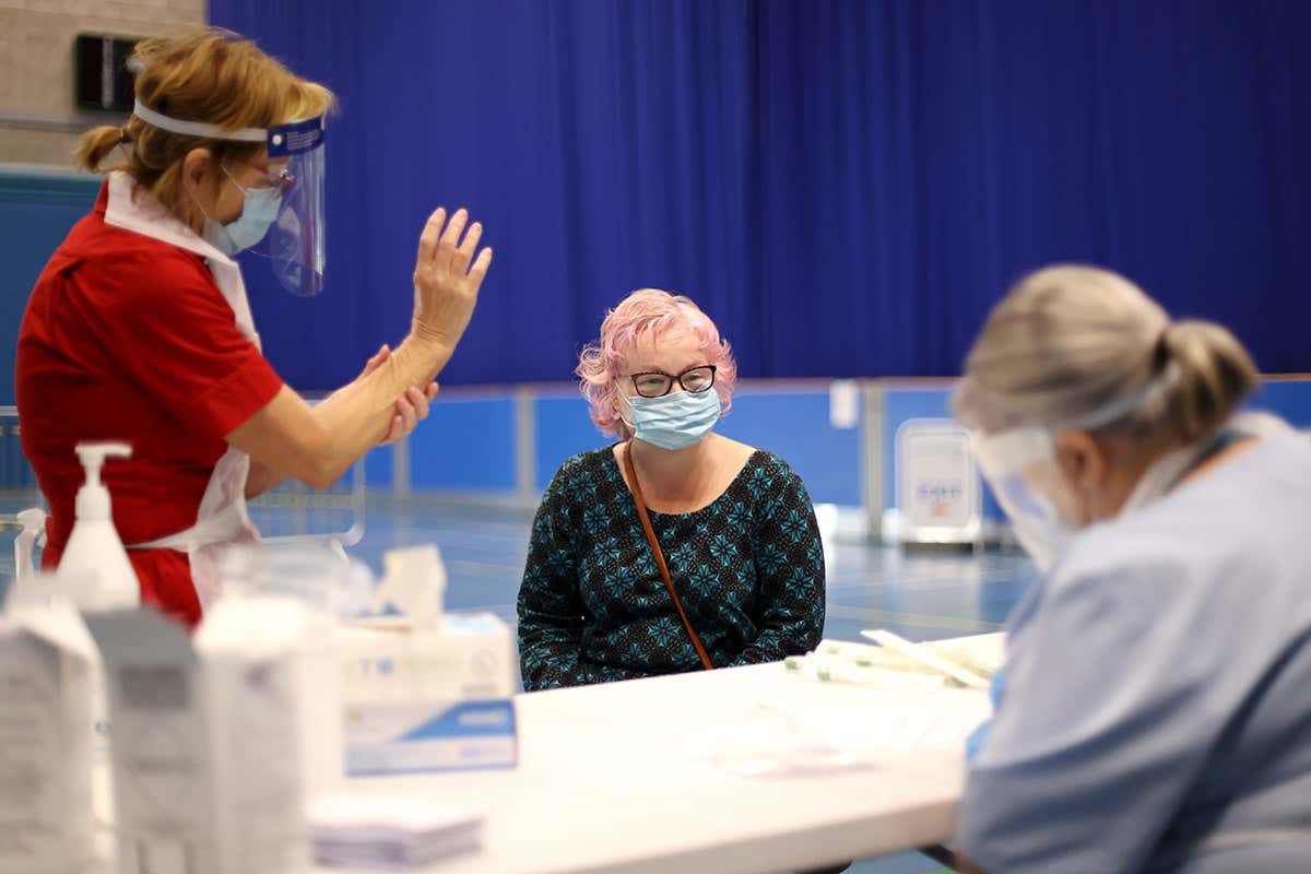 Two health workers speak with a woman before conducting a test for the coronavirus in Stoke-on-Trent, UK
