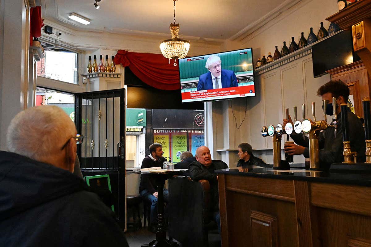 A television shows Britain's Prime Minister Boris Johnson speaking in the House of Commons in London, as customers sit at tables inside the Richmond Pub in Liverpool, north west England on October 12, 2020