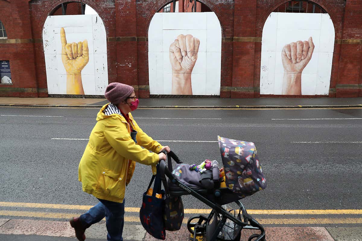 A woman pushing a baby stroller walks on a street during stricter restrictions due to the coronavirus outbreak in Sheffield, UK