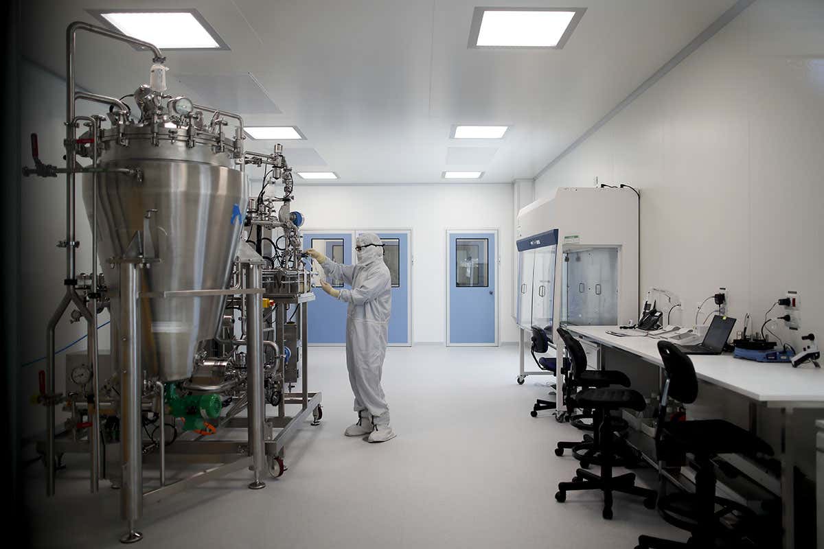 A laboratory technician wearing personal protective equipment works in a laboratory