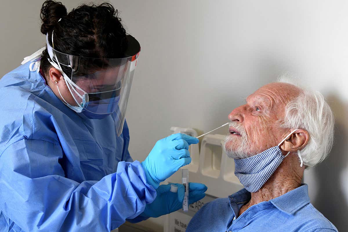 A nurse wearing personal protective equipment performs a coronavirus nose swab test on a participant in the Moderna covid-19 vaccine study in Miami