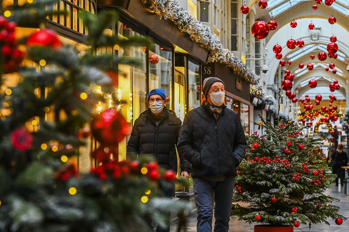 Two people wearing face coverings walk along a shopping arcade in London, UK