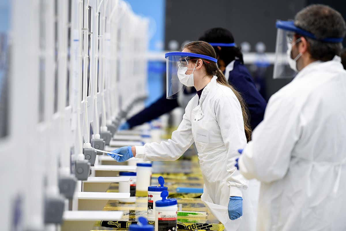 Students at the University of St Andrews in Scotland wearing personal protective equipment participate in the testing of a lateral flow antigen test facility
