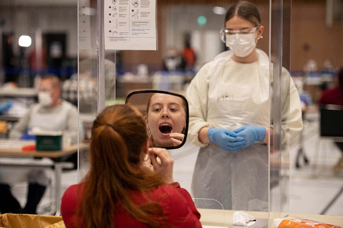 A student looks in the mirror as they take a swab for a lateral flow covid-19 test at a new asymptomatic testing site at the University of Hull in England