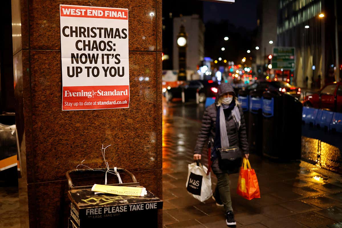 A shopper walks past an Evening Standard newspaper stand in central London on 16 December, as new guidance on Christmas during the coronavirus pandemic was announced by the government. A poster advertising the newspaper stand reads: "Christmas chaos: now it's up to you"