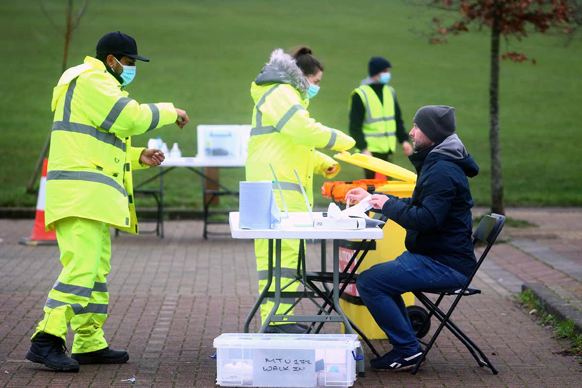 A health worker talks with a man taking a swab test in a park