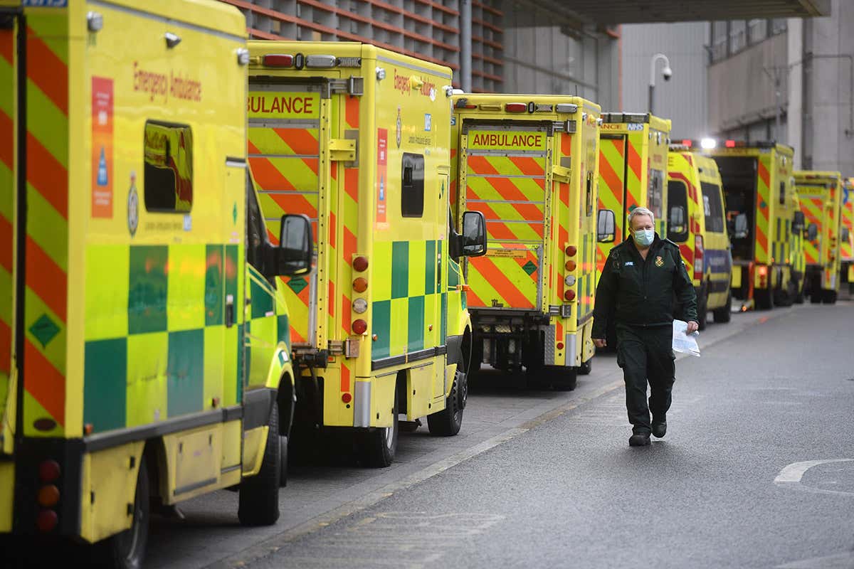 A healthcare worker walks past a line of ambulances at the Royal London Hospital in London, UK