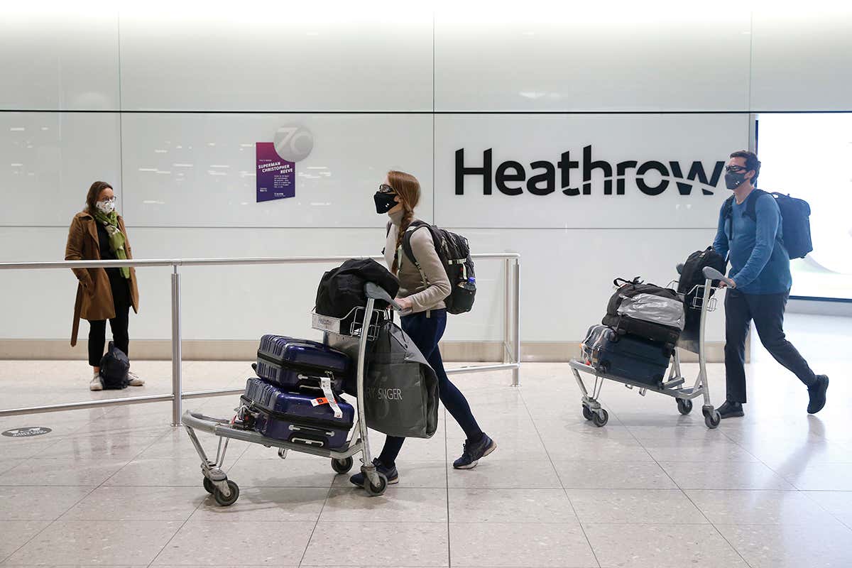 Passengers push luggage on trolleys through a terminal at London's Heathrow airport
