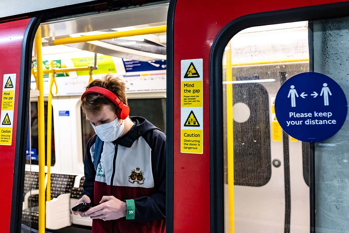 A man wearing a face mask travels on a London tube