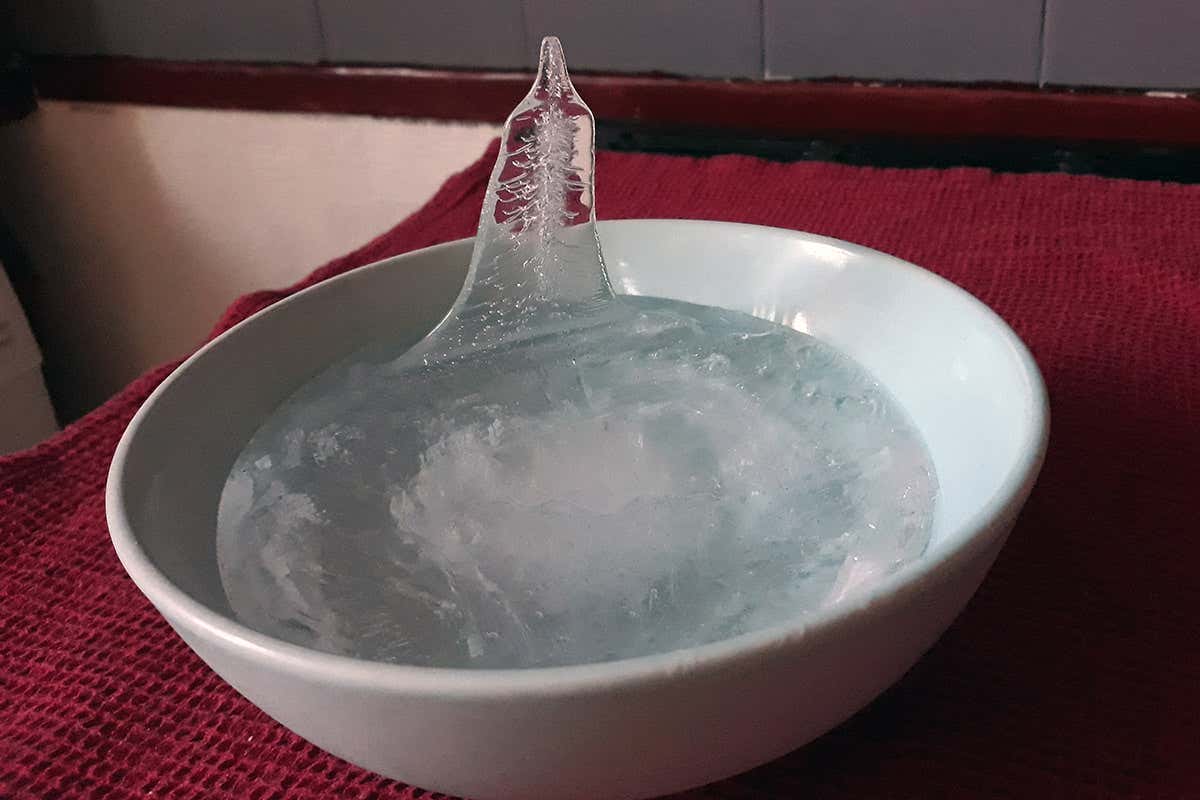 What causes ice spikes to form in frozen puddles or bowls of water?