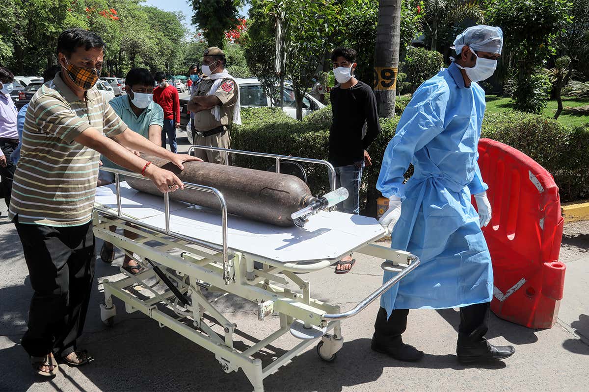 Health care workers move an oxygen cylinder on a stretcher at Jaipur Golden Hospital in Delhi, India.