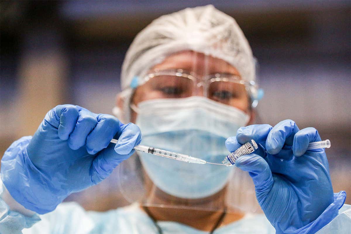 A medical worker transfers a dose of covid-19 vaccine at the Makati Coliseum in the Philippines