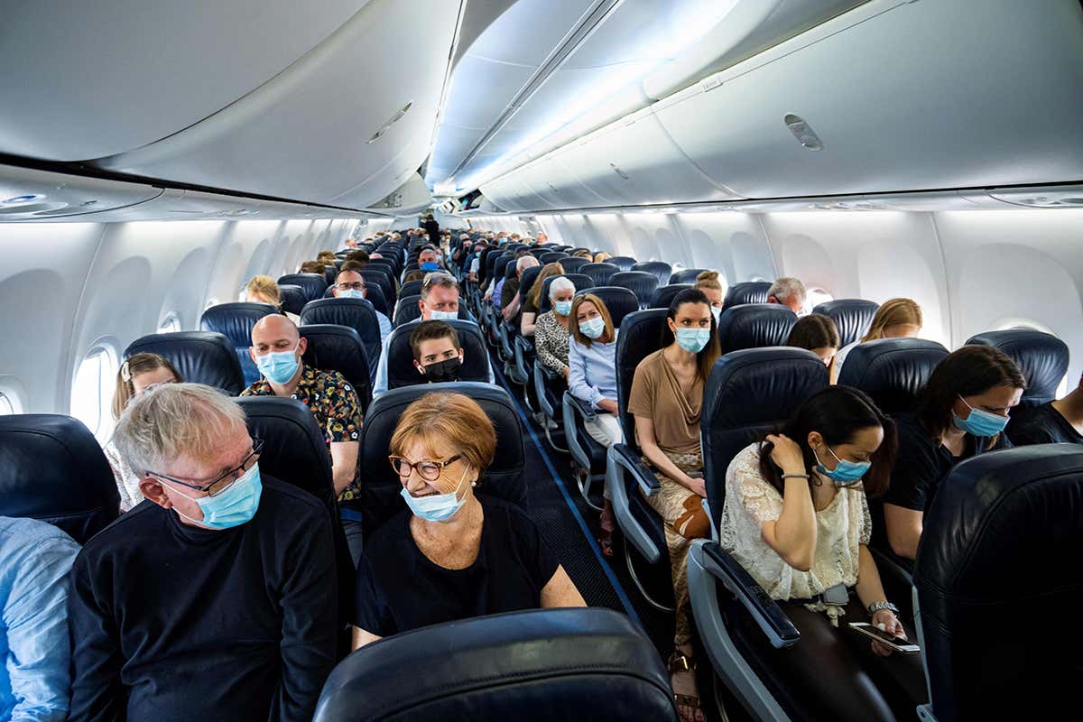 Passengers wearing facemasks sit on a plane departing from Denmark