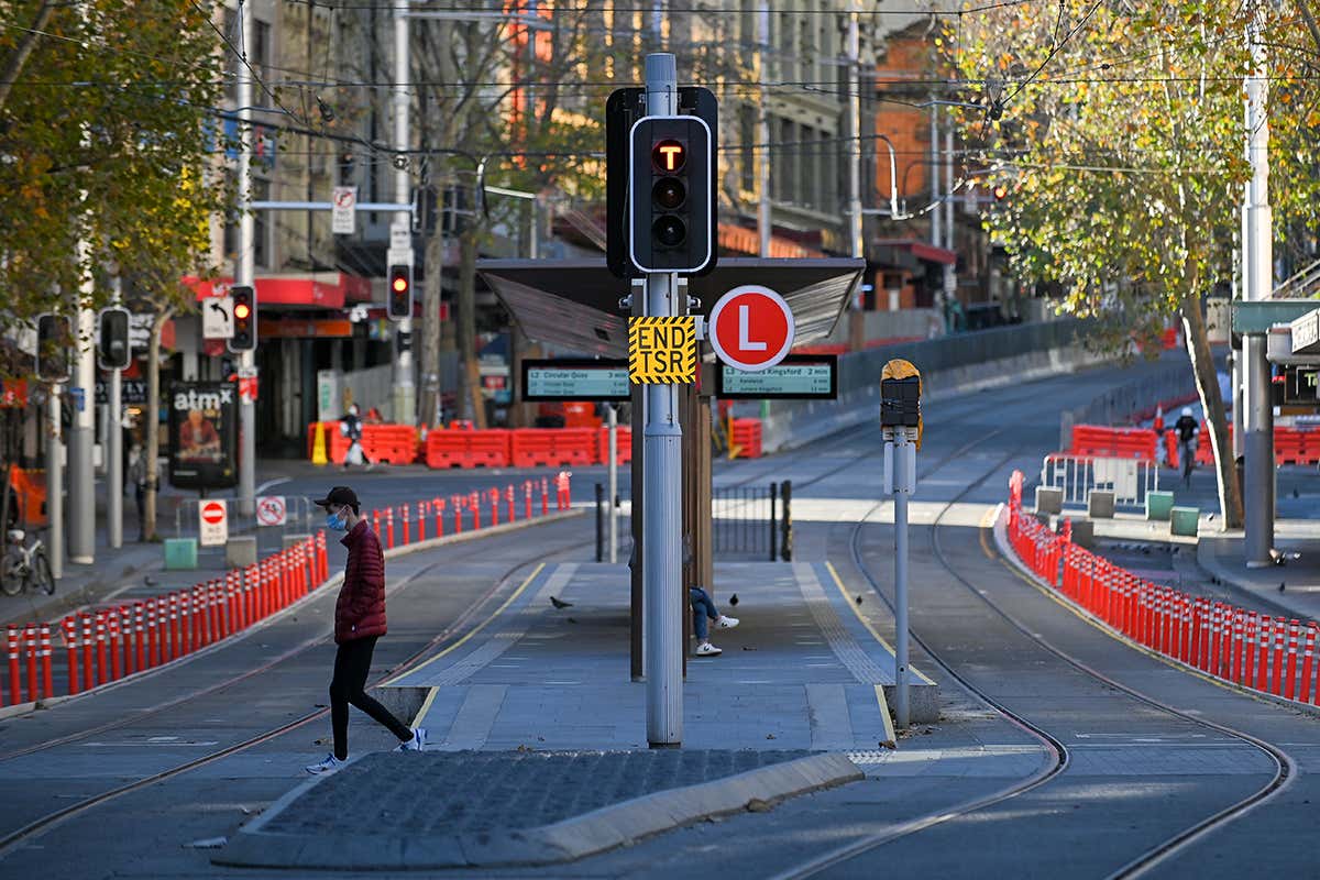 A man crosses the tracks at a tram station in the empty central business district in Sydney