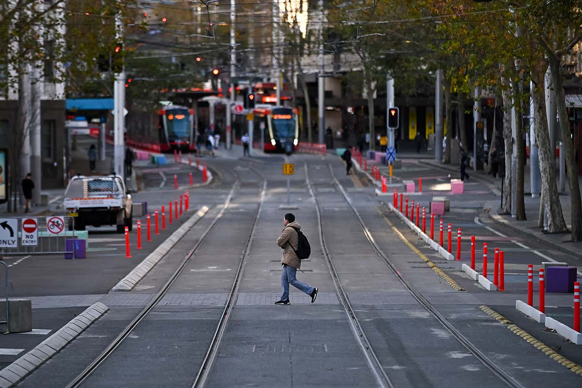 A man crosses an empty street during lockdown in Sydney, Australia