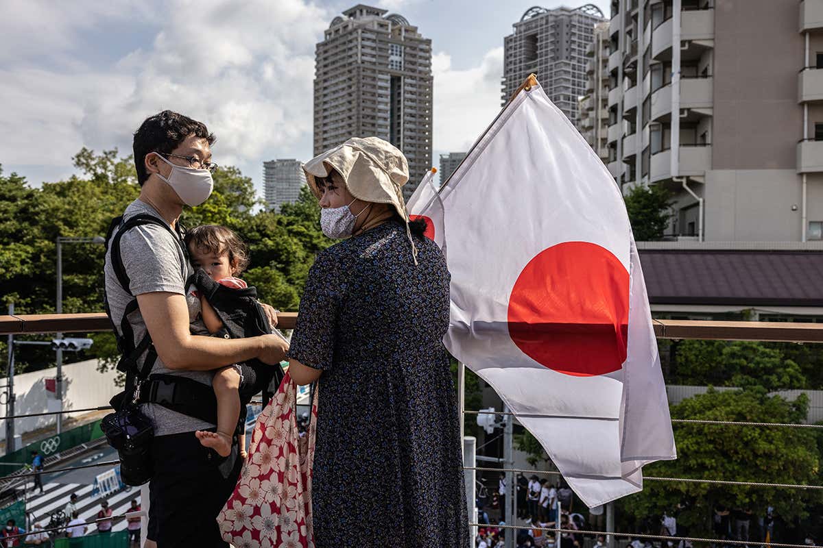 Spectators in Tokyo wait to see triathlon relay competitors on 31 July