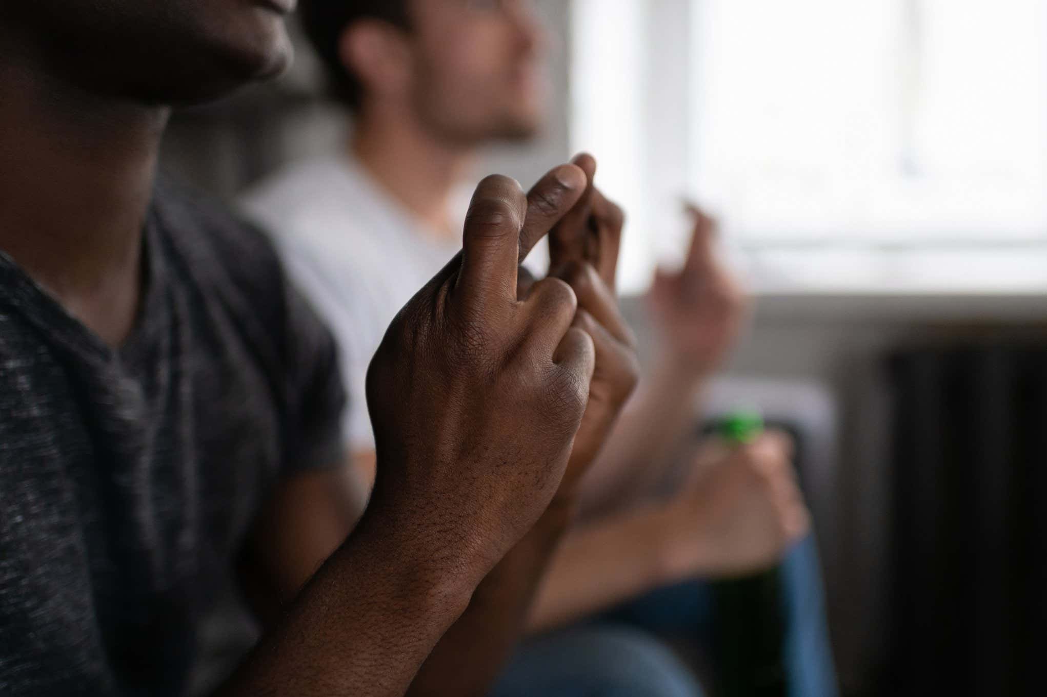 Unrecognizable African American guy crossing fingers while supporting football team with blurred friend while watching match in field (Unrecognizable African American guy crossing fingers while supporting football team with blurred friend while watchi