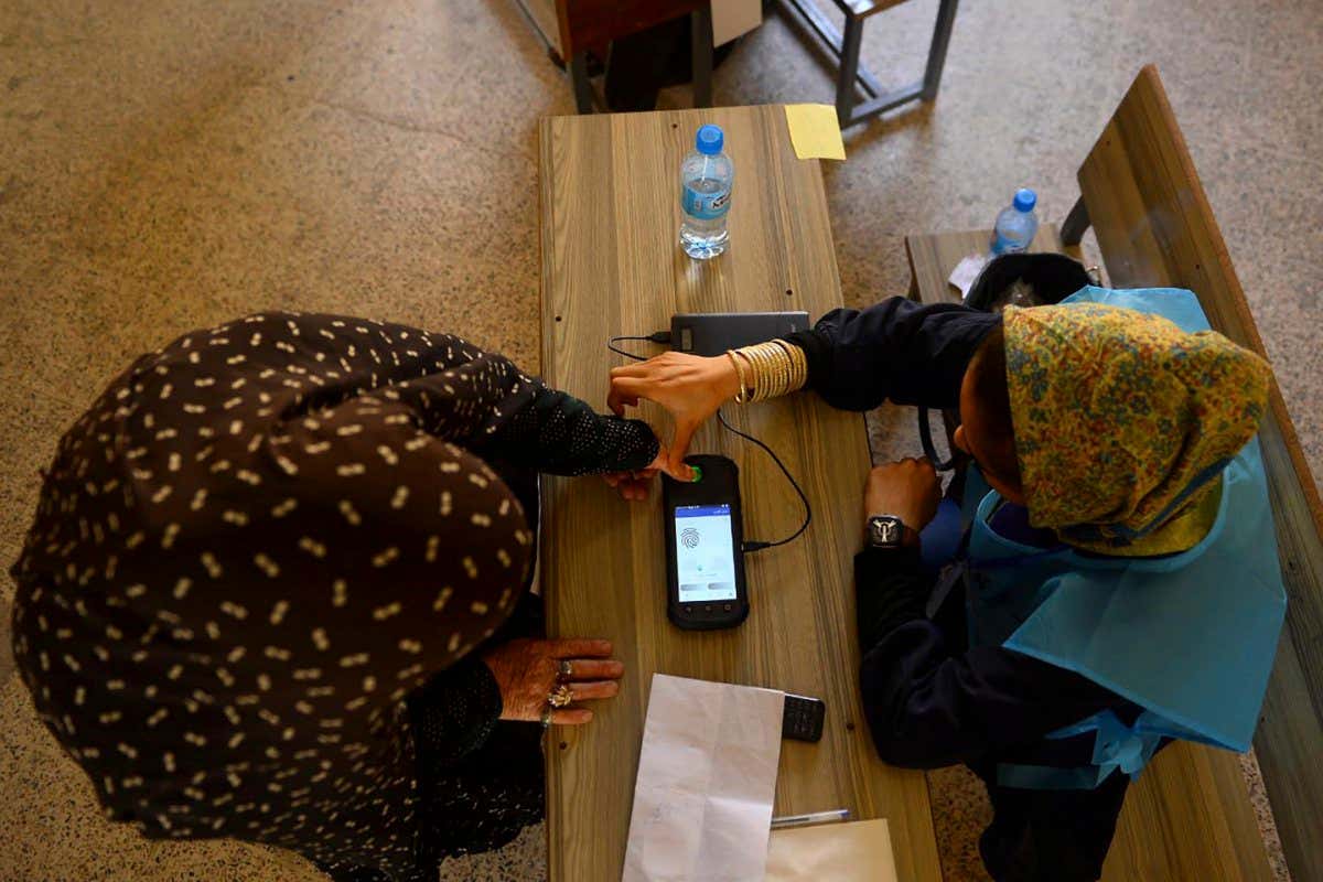 An Independent Election Commission (IEC) official (L) scans a finger of a voter with a biometric device at a polling station in Herat on September 28, 2019. - Afghans voted in presidential elections amid tight security on September 28, even as insurgents attacked polling centres in a series of blasts and clashes across the country that left at least two people dead. (Photo by HOSHANG HASHIMI / AFP) (Photo credit should read HOSHANG HASHIMI/AFP via Getty Images)