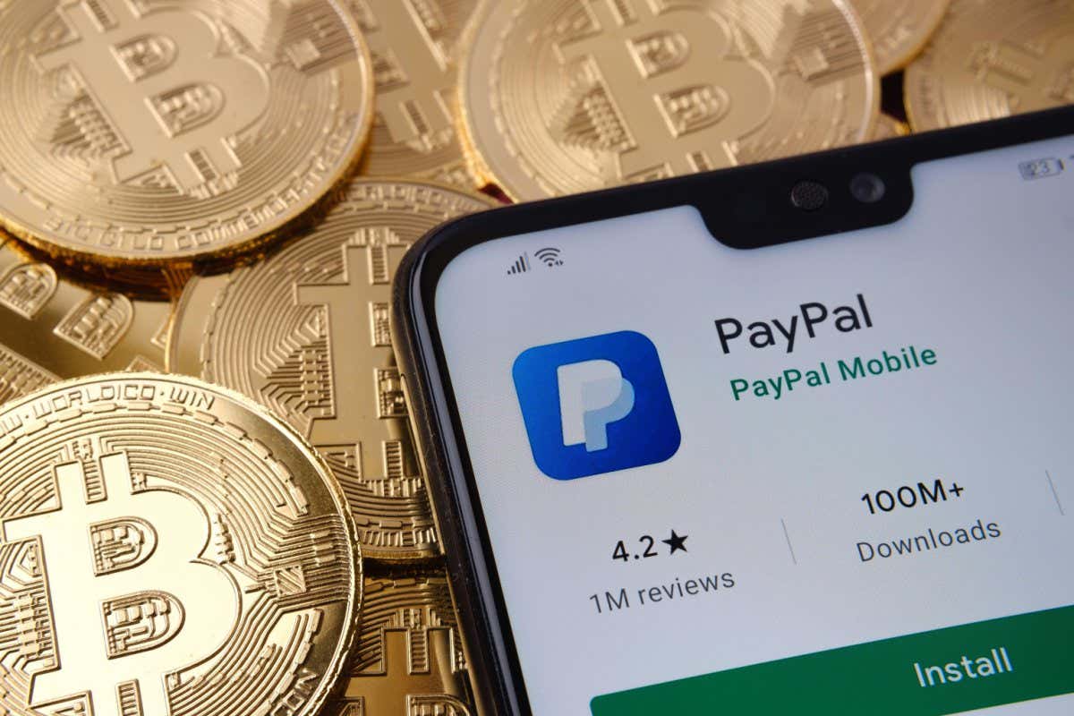 2F8A64A Paypal app seen on the smartphone screen placed on top bitcoin coins pile. Concept. Stafford, United Kingdom, April 12, 2021.