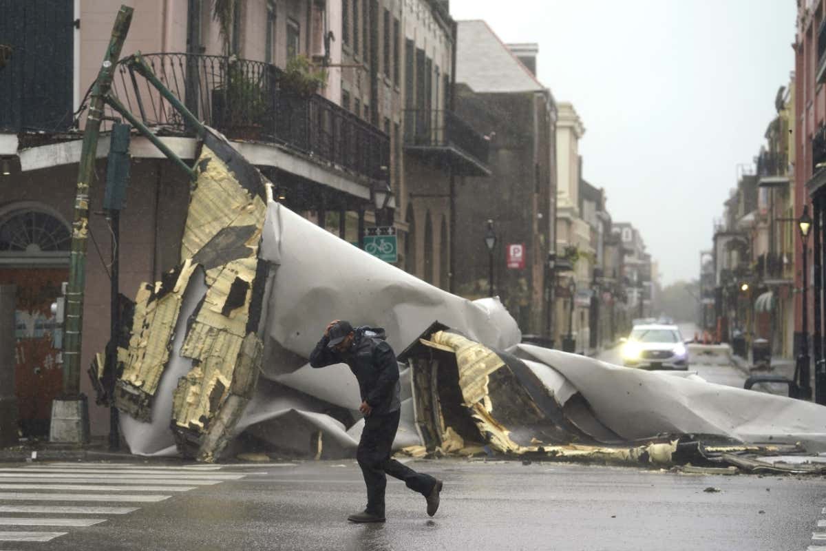 Man passes by a section of roof that was blown off of a building by Hurricane Ida, in New Orleans