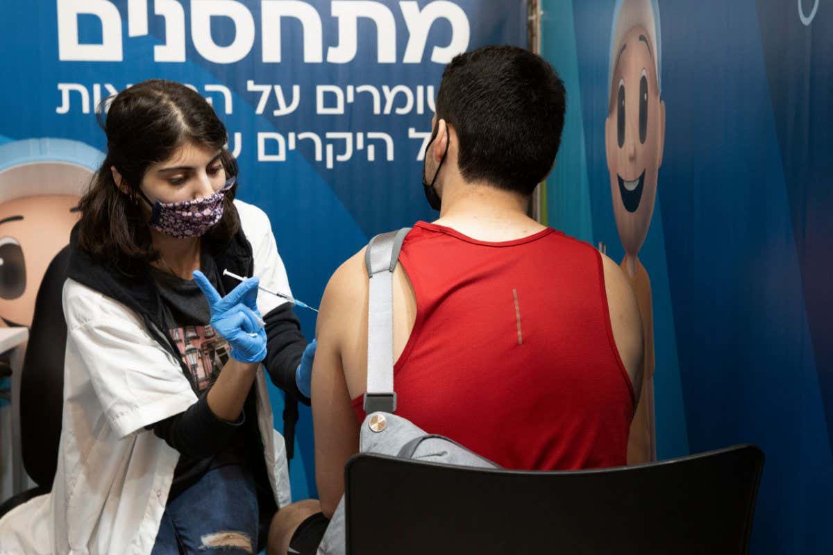 An Israeli man receives a booster shot of the coronavirus vaccine from a medical professional with Clalit Health Services at the Cinema City complex in Jerusalem Virus Outbreak , Jerusalem, Israel - 30 Aug 2021