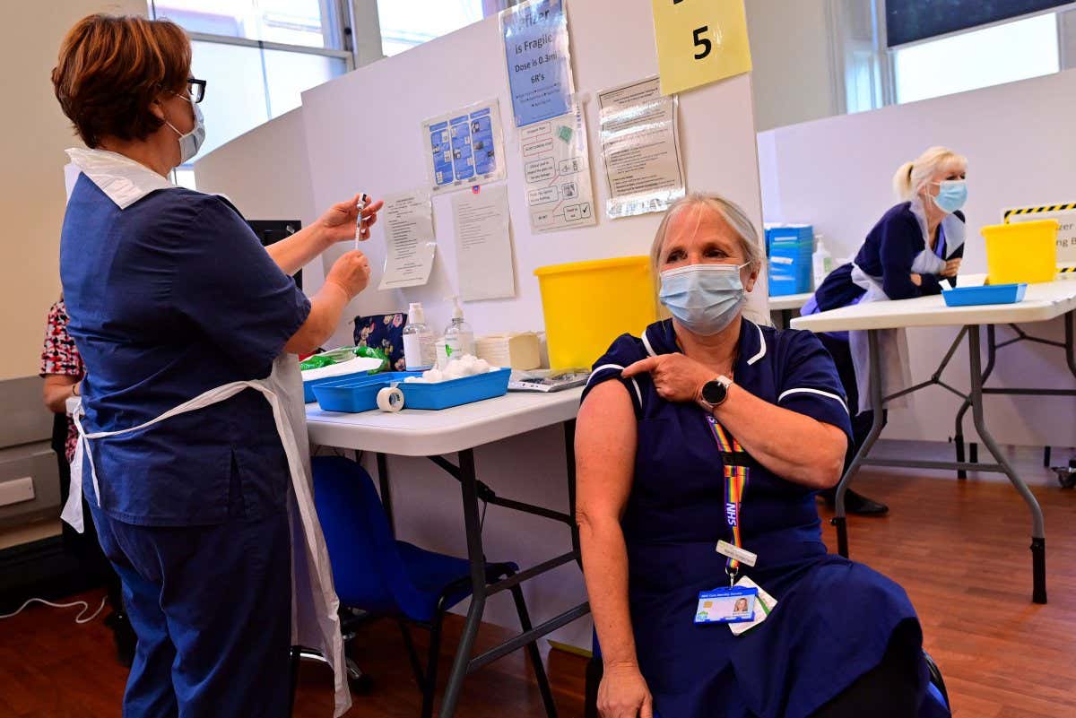 A nurse (L) prepares to administer a Pfizer booster vaccine to at a vaccination centre in Derby, central England on September 20, 2021. - Frontline health and social care workers, older people and the clinically vulnerable in Britain started on Monday to receive a booster jab against Covid 19. (Photo by Paul ELLIS / AFP) (Photo by PAUL ELLIS/AFP via Getty Images)
