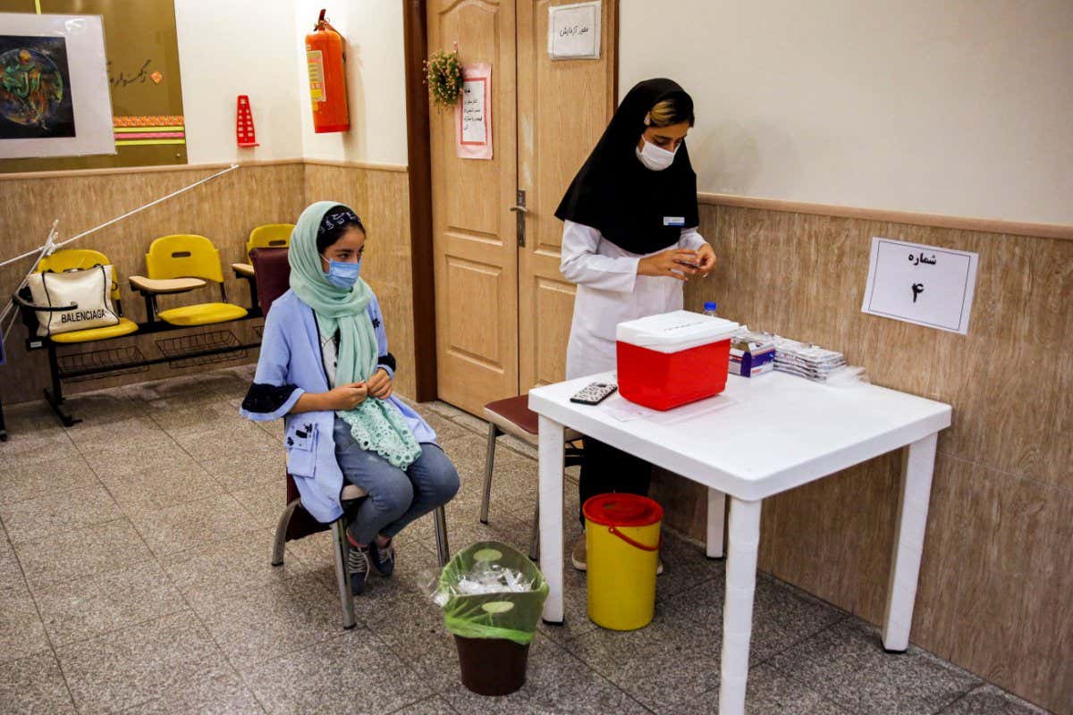 A student waits to receive a COVID-19 coronavirus vaccine dose at a vaccination centre set up inside a school in Iran's capital Tehran on October 7, 2021. (Photo by - / AFP) (Photo by -/AFP via Getty Images)