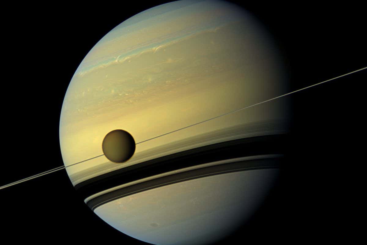 A giant of a moon appears before a giant of a planet undergoing seasonal changes in this natural color view of Titan and Saturn from NASA Cassini spacecraft.