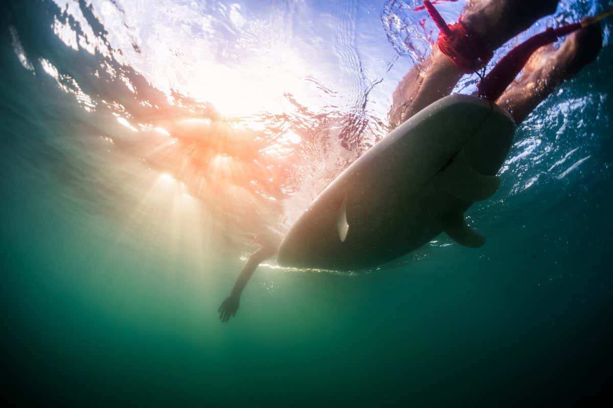Underwater view of someone paddling on a surfboard