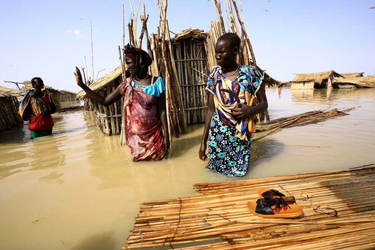 South Sudanese refugees try to repair their hut in flooded waters from the White Nile at a refugee camp which was inundated after heavy rain near in al-Qanaa in southern Sudan, on September 14, 2021. - Nearly 50 villages have been submerged in southern Sudan, displacing some 65,000 people including South Sudanese refugees whose camp was inundated, the UN said in a report last week. (Photo by ASHRAF SHAZLY / AFP) (Photo by ASHRAF SHAZLY/AFP via Getty Images)