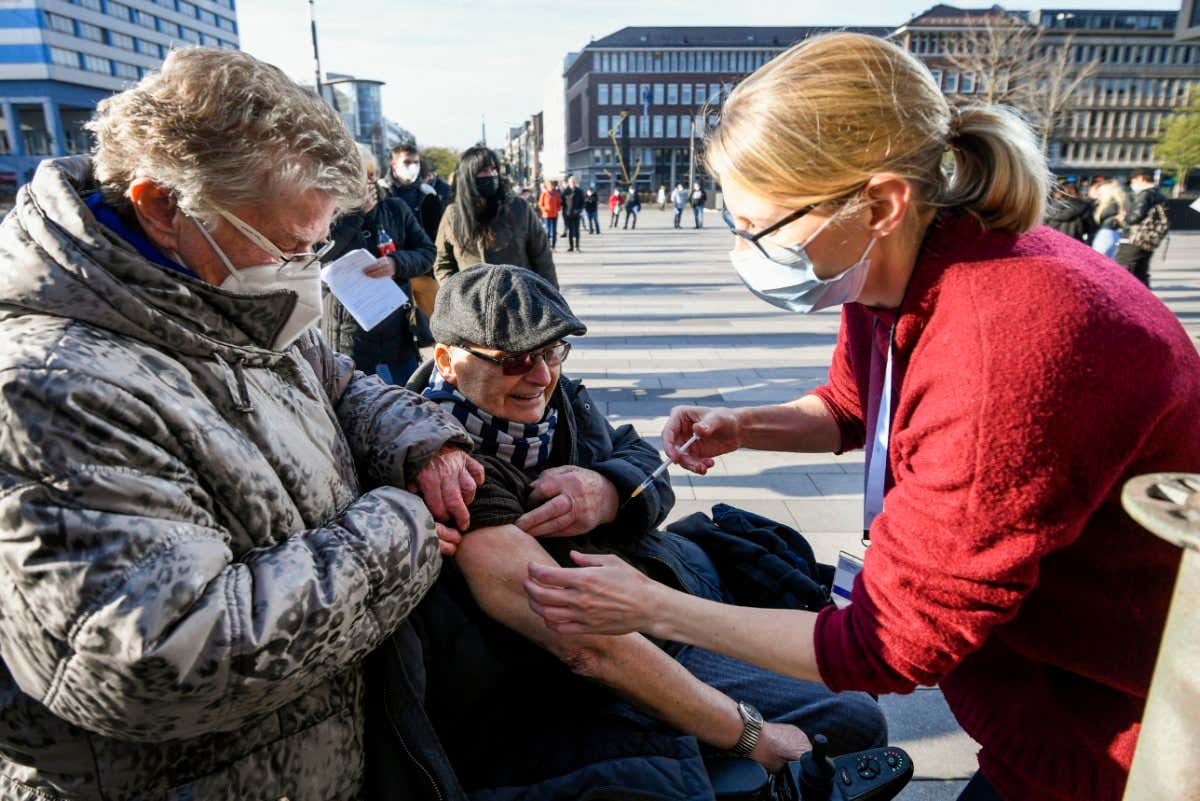 A man in a wheelchair is vaccinated outside a mobile vaccination center set up in the city of Duisburg, western Germany