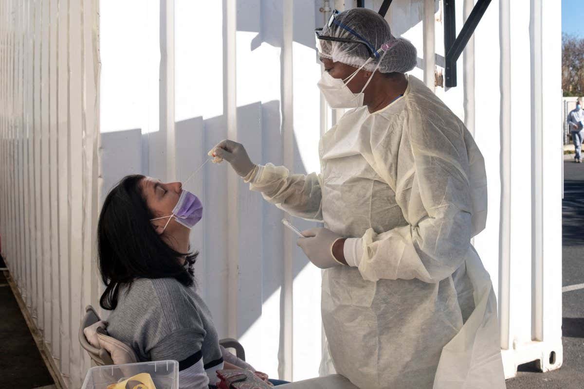 A woman in Johannesburg receives a nasal swab from a health worker
