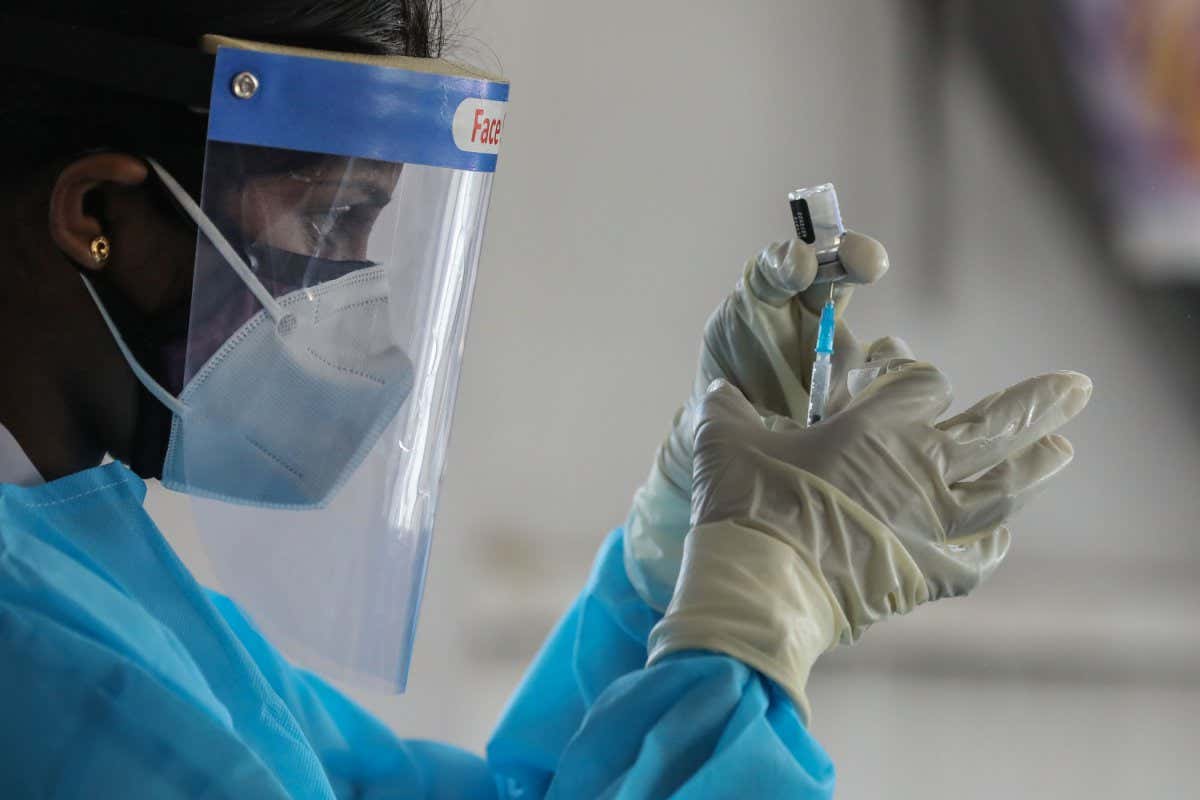 A health worker holds a vial of the Pfizer/BioNTech vaccine