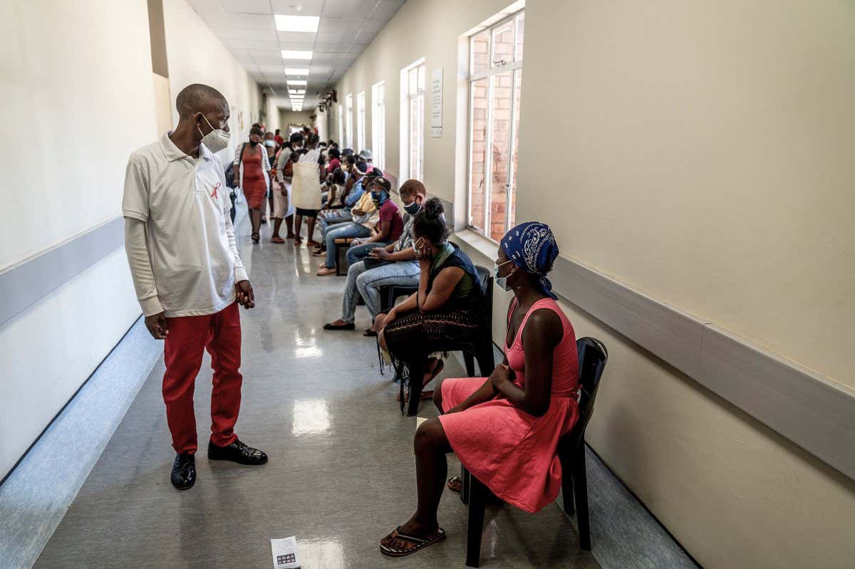 Mandatory Credit: Photo by Shiraaz Mohamed/AP/Shutterstock (12626412b) Hospital worker ensures people practice social distancing as they wait in line to get vaccinated against COVID-19 at the Lenasia South Hospital, near Johannesburg, South Africa, . Despite the global worry, doctors in South Africa are reporting patients with the omicron variant are suffering mostly mild symptoms so far. But they warn that it is early Virus outbreak , Lenasia, South Africa - 30 Nov 2021