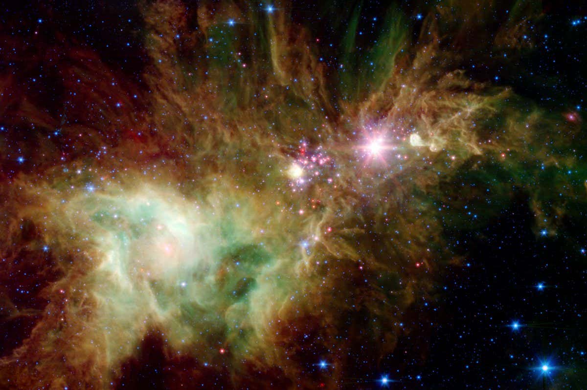Newborn stars, hidden behind thick dust, are revealed in this image of a section of the so-called Christmas Tree Cluster from NASA's Spitzer Space Telescope. The newly revealed infant stars appear as pink and red specks toward the center and appear to have formed in regularly spaced intervals along linear structures in a configuration that resembles the spokes of a wheel or the pattern of a snowflake. Hence, astronomers have nicknamed this the 