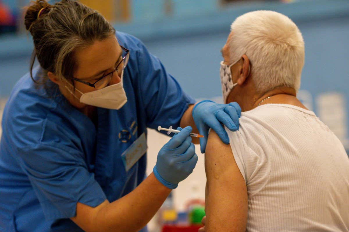 CWMBRAN, WALES - OCTOBER 05: A nurse administers a vaccine booster on October 05, 2021 in Cwmbran, Wales. Patients who attend the vaccine centre are also being offered the option of a flu vaccine. The Welsh Government has also announced that all 12 to 15-year-olds will be invited by letter to have the vaccine and the majority being administered at mass vaccination centres. In some areas, vaccination will be carried out at schools. (Photo by Huw Fairclough/Getty Images)