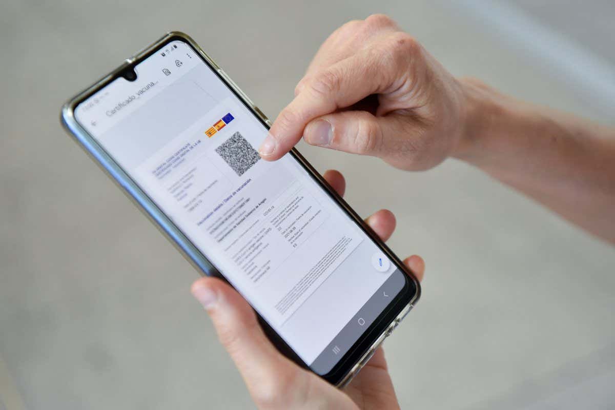 A woman checks her EU Digital Covid certificate on her mobilephone at El Prat airport in Barcelona on July 1, 2021. - The European health certificate, which Belgium began using on June 16, 2021, will become operational across the EU on July 1, 2021. (Photo by Pau BARRENA / AFP) (Photo by PAU BARRENA/AFP via Getty Images)