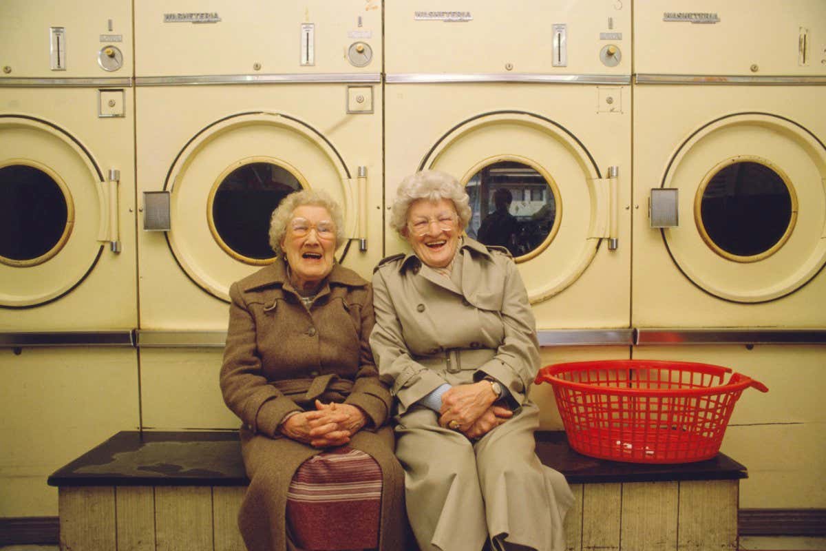 Two senior woman in launderettes, laughing, portrait