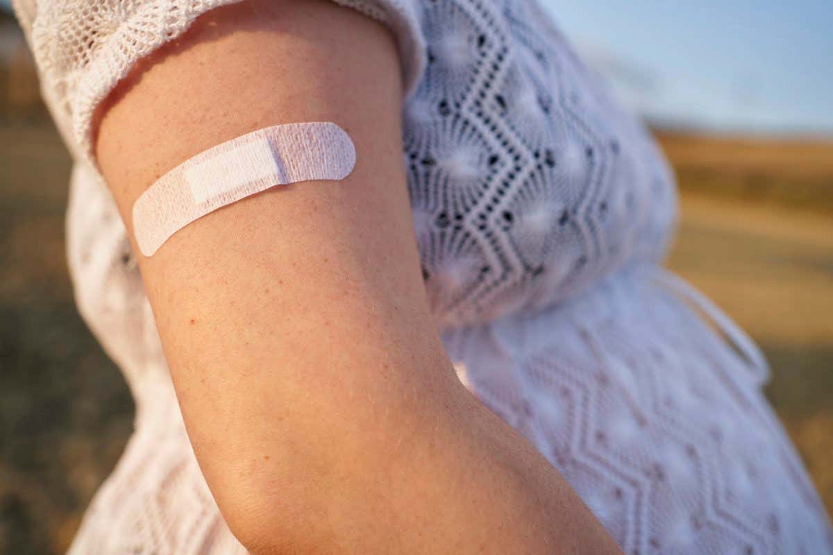 Close-up of band aid, on the arm young pregnant woman after giving her the vaccine. vaccine and pregnant concept