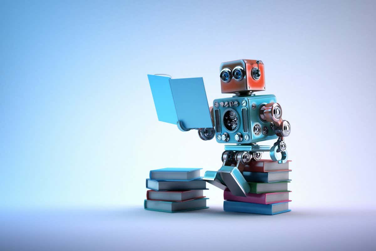 Robot sitting on a bunch of books. Contains clipping path